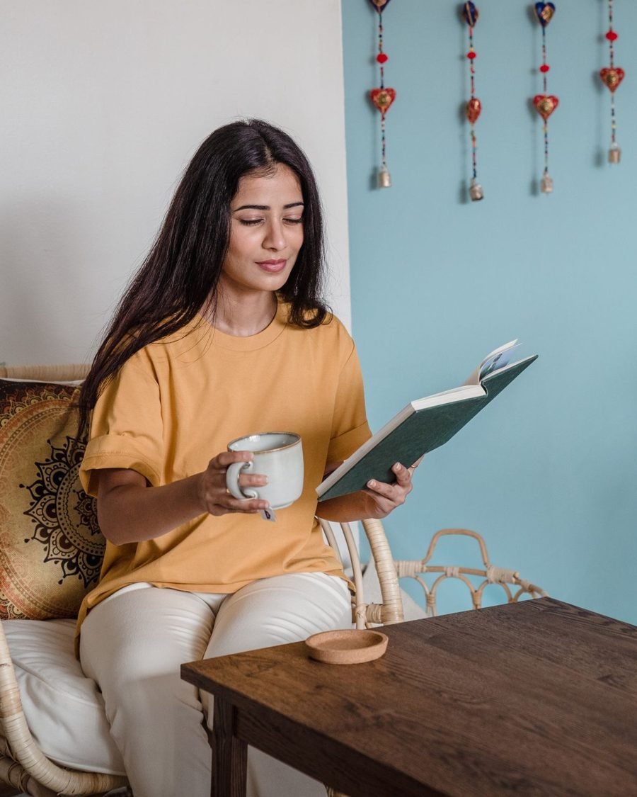 Woman reading a book with a cup of tea at home