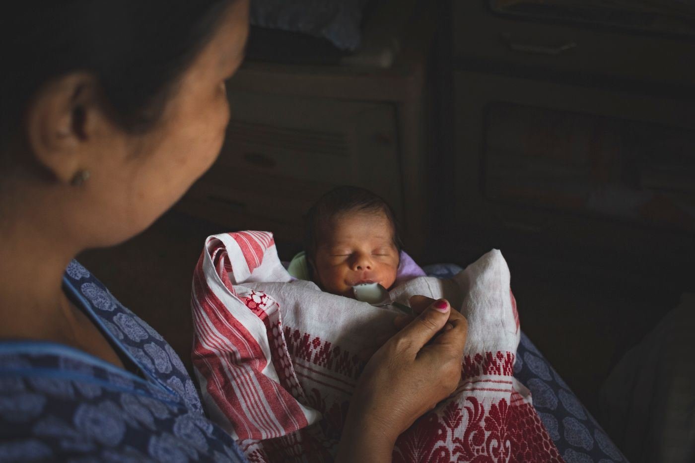 Mother looking at her newborn baby wrapped in a blanket