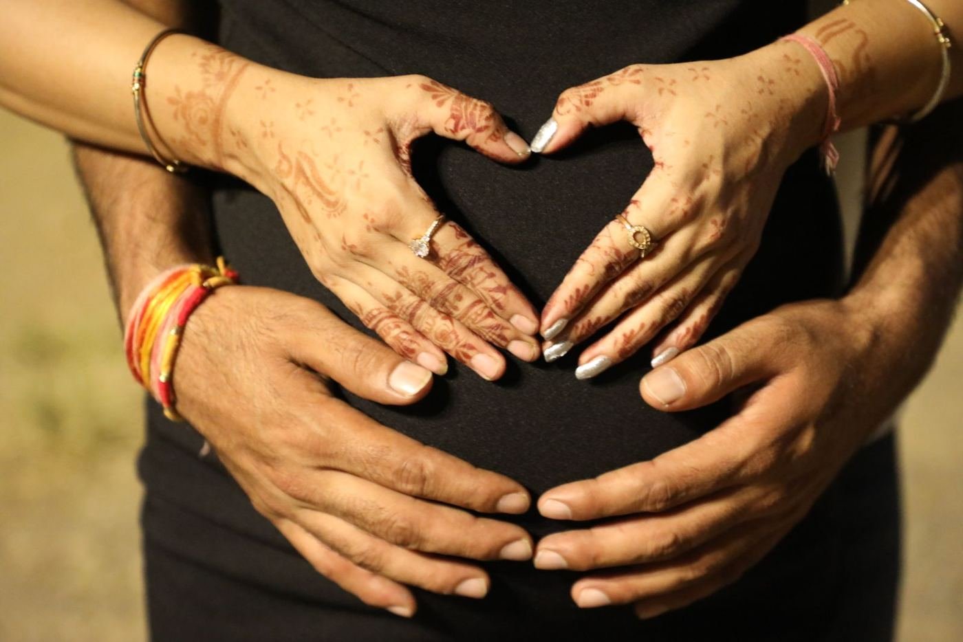 Couple's hands forming a heart over a pregnant belly